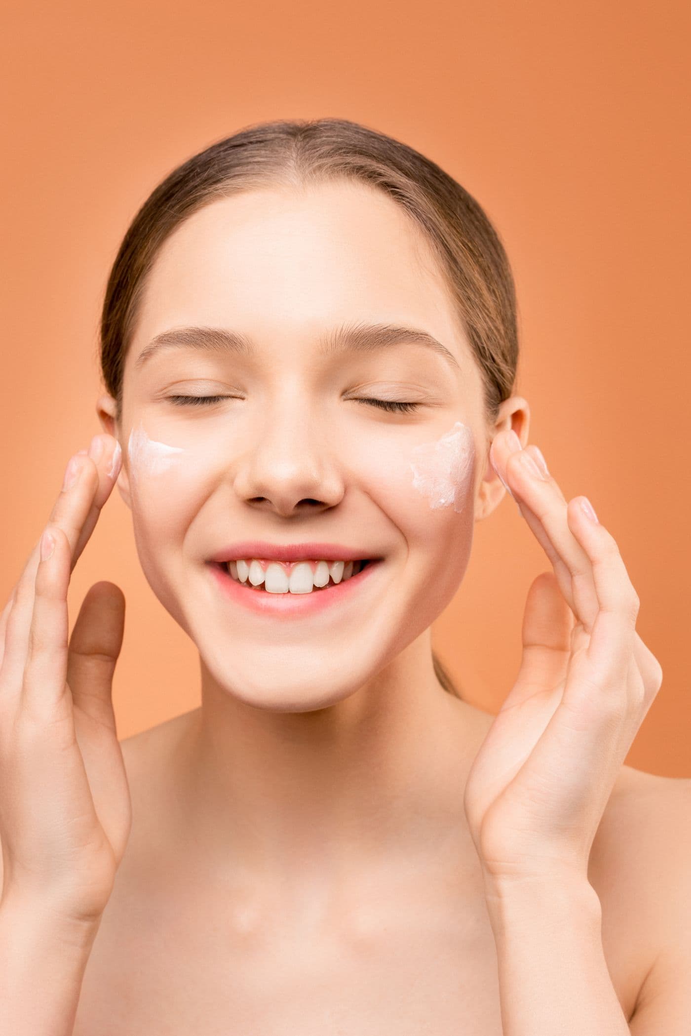 Mujer sonriente aplicándose su ritual de skincare